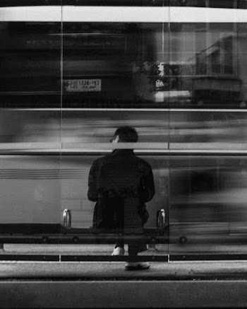 Grayscale Photography of Person Sitting on Bench