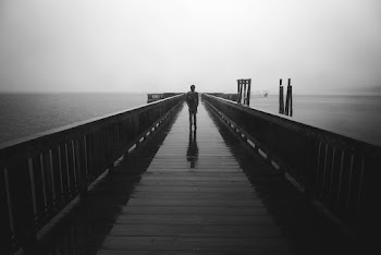 Grayscale Photography of Person Standing on Bridge