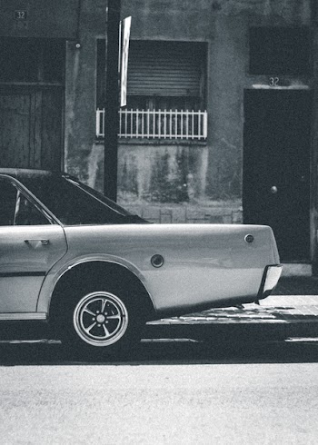 Grayscale Photography Of Sedan On Roadside