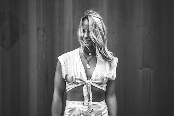 Grayscale Photography of Smiling Woman Standing Near Wall