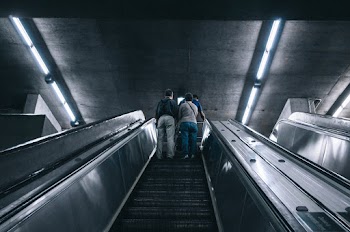Grayscale Photography of Two Person on Escalator