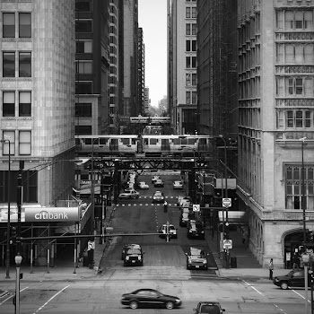 grayscale photography of vehicles between high rise buildings