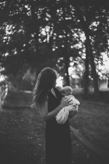 grayscale photography of woman carrying her child