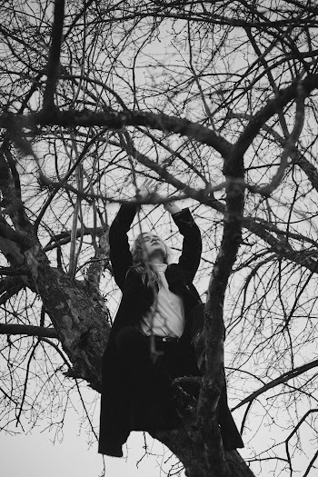 Grayscale Photography of Woman Climbing on Bare Tree