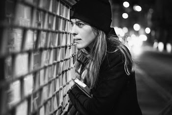 grayscale photography of woman looking outside glass wall