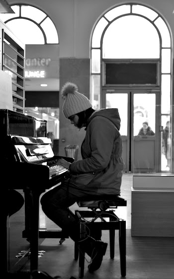 Grayscale Photography of Woman Sitting in Front of a Piano