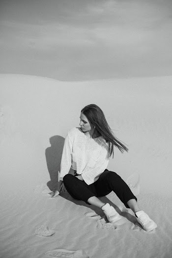 Grayscale Photography of Woman Sitting on Sand
