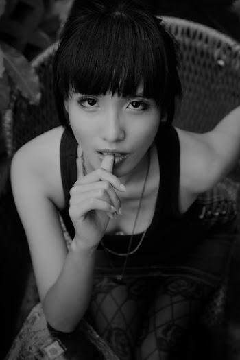 Grayscale Photography of Woman Sitting While Biting Right Thumb