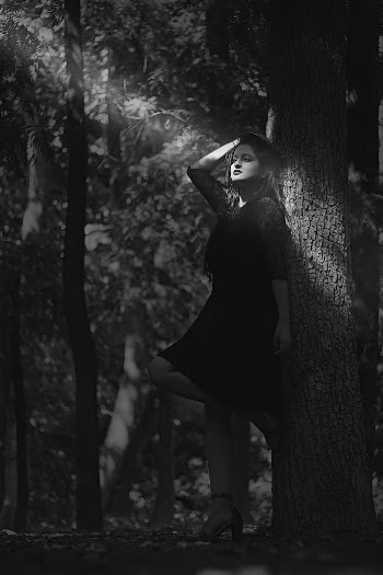 Grayscale Photography of Woman Standing and Leaning Against Tree