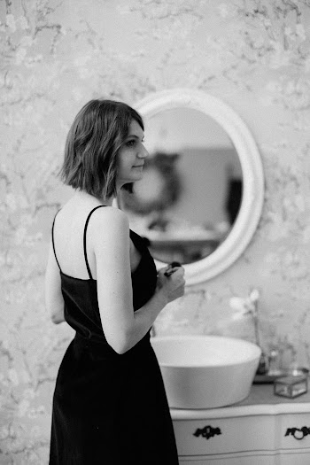 Grayscale Photography of Woman Standing in Front of a Vanity Sink