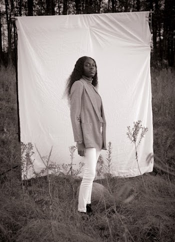 Grayscale Photography of Woman Standing in Front of White Sheet