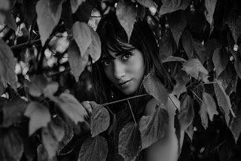 Grayscale Photography of Woman Standing Near Leaves