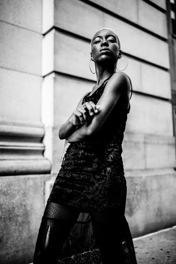 grayscale photography of woman standing near wall