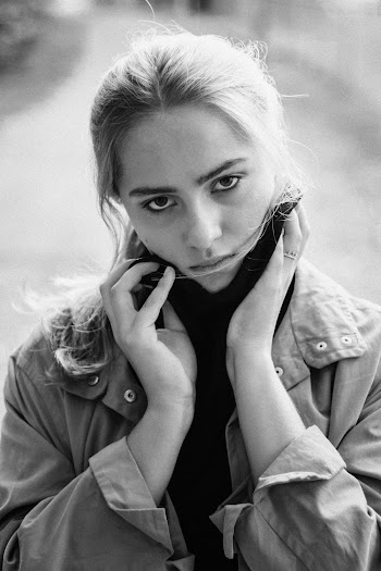 Grayscale Photography of Woman Wearing Jacket Touching Her Face
