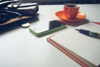 Green and Black Android Smartphone on Table Near Notebook