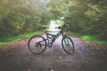 green and black full-suspension bicycle park on center of pathway during day time