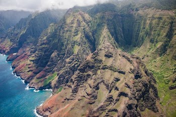 green and brown mountain near body of water in aerial photography