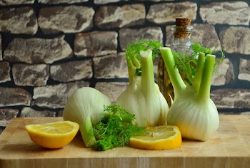 Green and White Onions and Sliced Lemons on a Brown Surface
