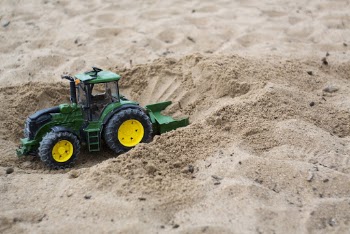 Green and Yellow Toy Bulldozer on Sand