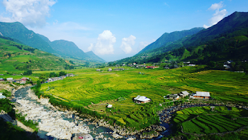 Green Fields Surrounded by Mountains Under Blue Cloudy Sky
