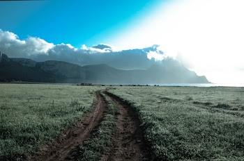 Green Grass Field Beside Brown Mountains Under White Cloudy Sky