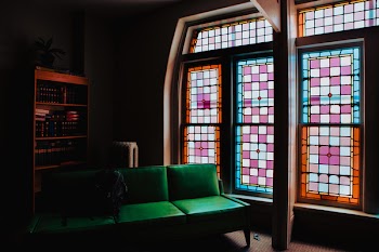 Green Leather Couch Beside of Stained Glass Window