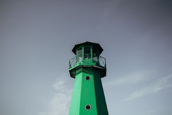 green lighthouse under cloudy sky during daytime