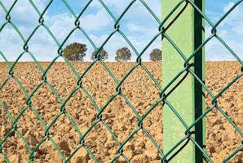 Green metal wire mesh against a field or private property