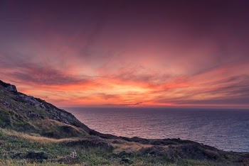 green mountain by the sea during sunset