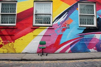 green padded rolling chair beside multicolored concrete wall