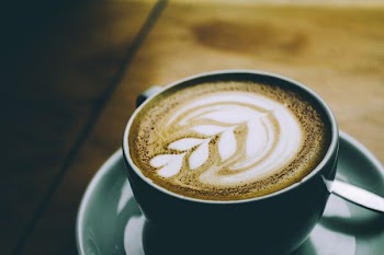 green teacup with latte and saucer