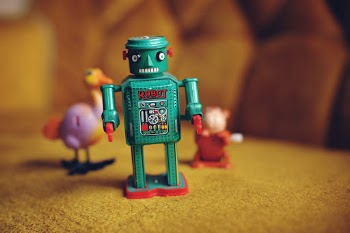 Green toy robot and its minions on a yellow couch.
