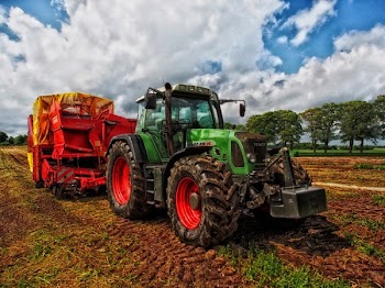 Green Tractor Pulling Red Bin on Field at Daytime
