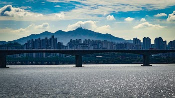 Grey Concrete Bridge Near Cities and Mountain at Daytime