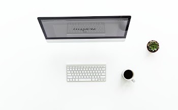 grey flat screen computer monitor near Apple magic keyboard and white ceramic mug