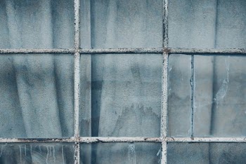 grey metal grill on clear glass window closeup photography