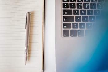 Grey Pen in White Lined Paper Beside Grey Laptop Computer