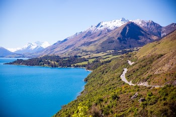 Grey Road Near Mountain Near Body of Water Photo