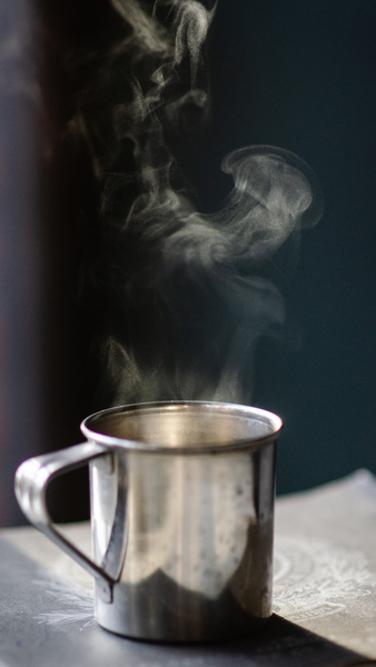 Grey Stainless Steel Mug Filled With Hot Liquid on Brown Surface