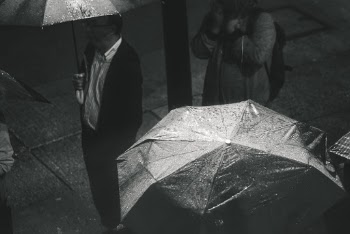 Greyscale Photo of Man Holding Umbrella While Raining