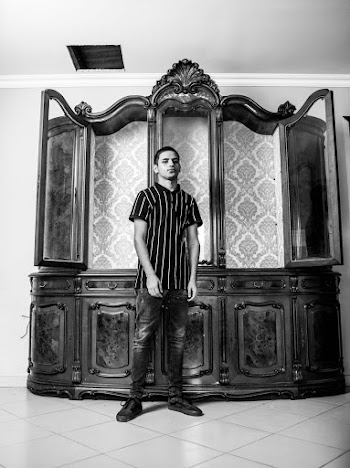 Greyscale Photo Of Man Standing Beside Cabinet
