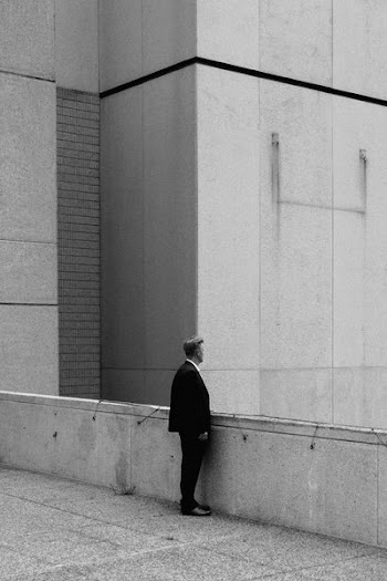 greyscale photo of man standing on bridge during daytime