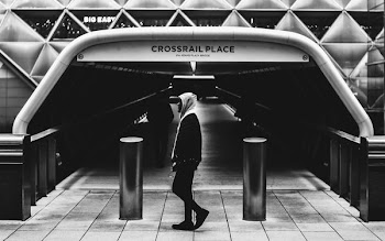 greyscale photo of person wearing hoodie at Crossrail Place