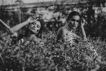 Greyscale Photo of Two Women Near Plants