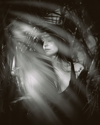 Greyscale Photography of Woman Behind Palm Leaves