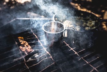 grilling meat beside stainless steel cup