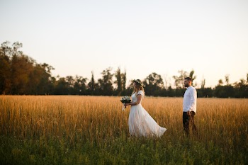 Groom Standing Next to Bride Holding Bouquet of Flower on Grass Field