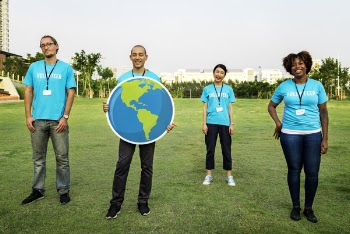 Group of Four People Wearing Blue Standing on Green Grass Field
