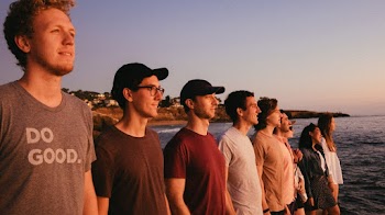 Group Of Men And Women Standing By The Beach