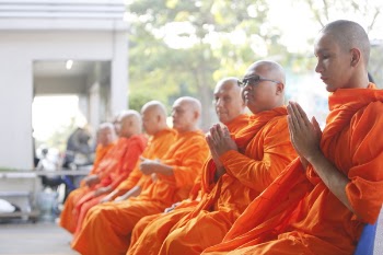 Group of Monks Sitting Near White Concrete Building